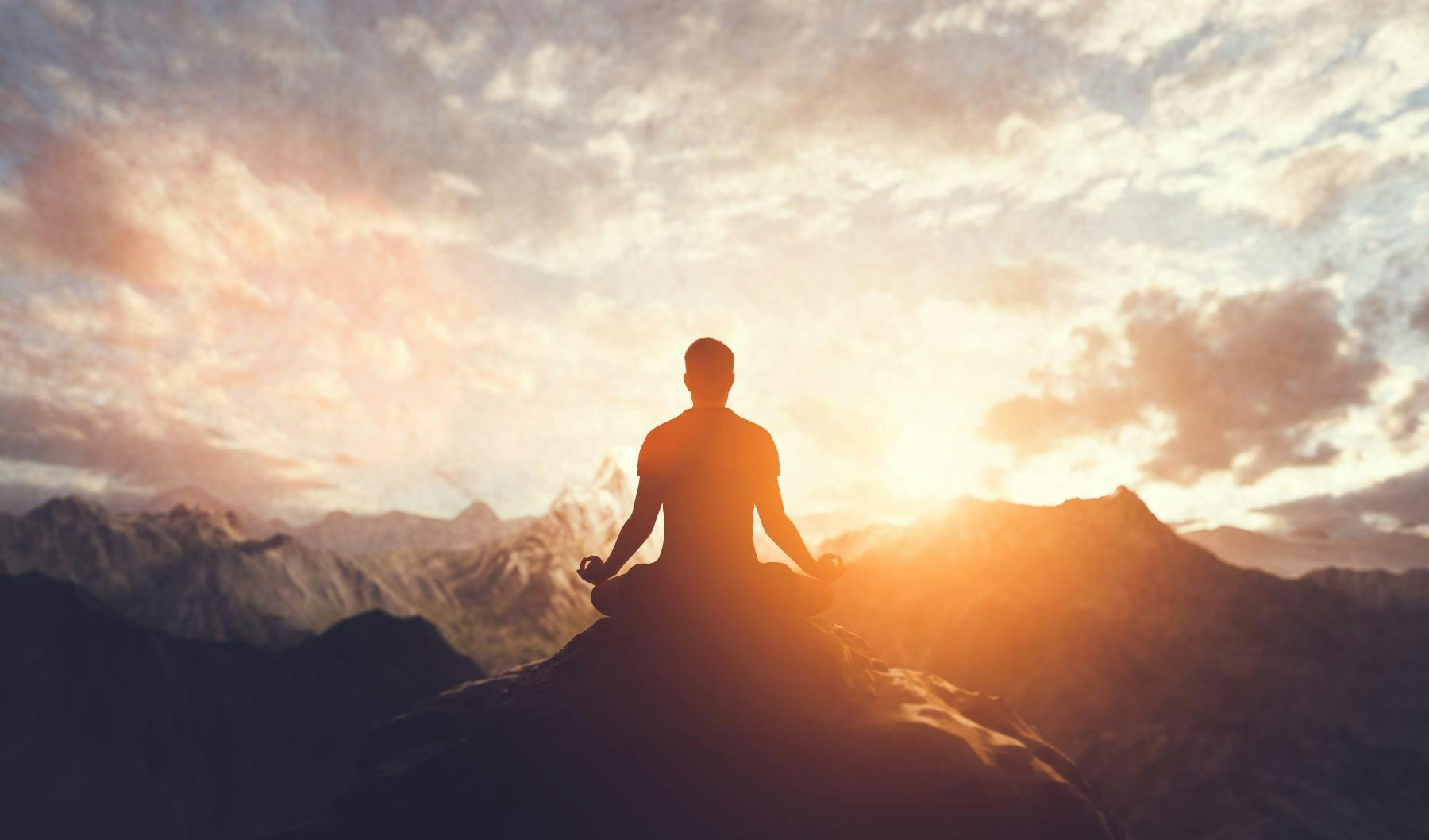 person meditating on mountaintop at sunrise
