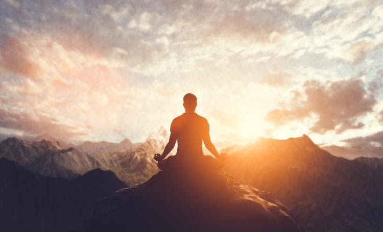 person meditating on mountaintop at sunrise