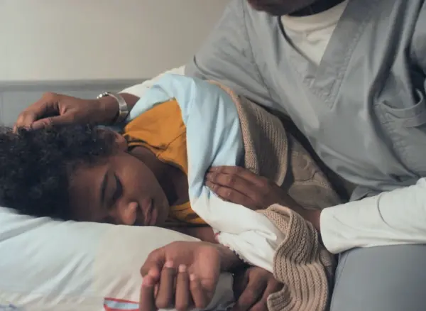 Caregiving child being covered with blanket